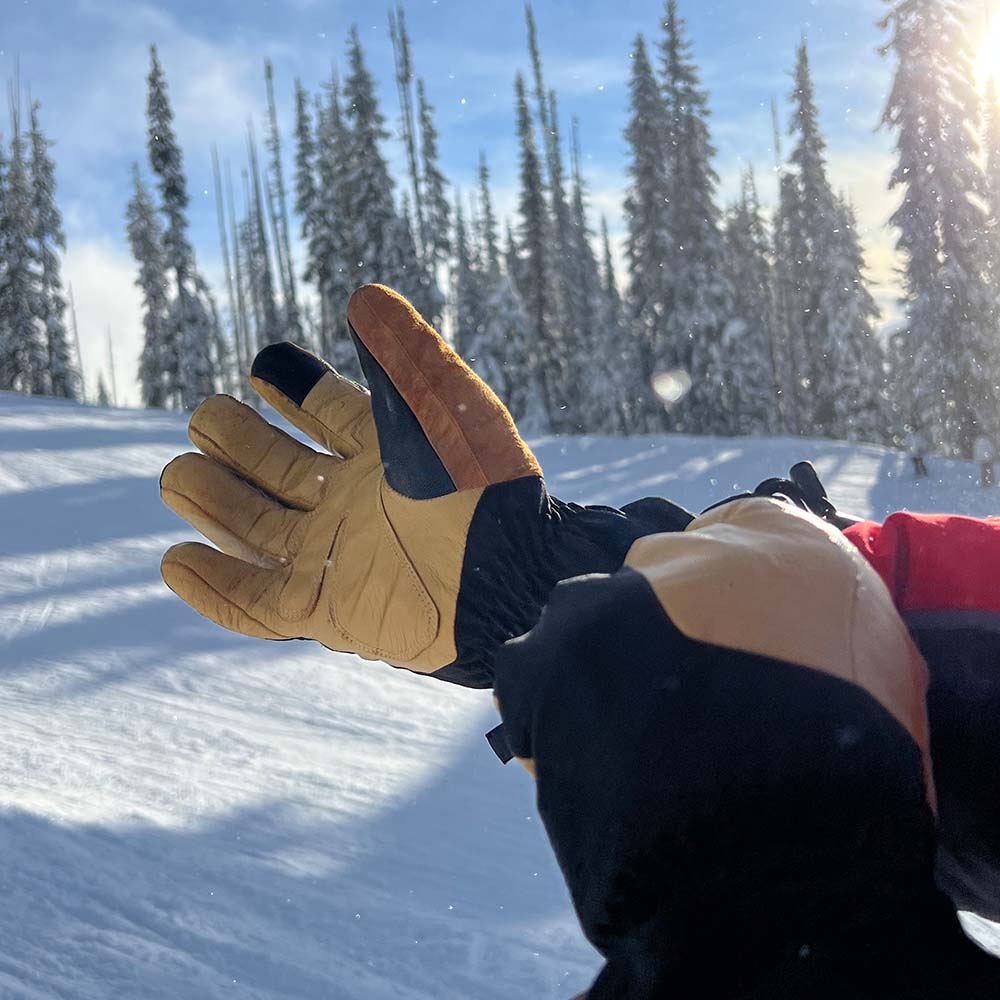A hand pulling on a merino wool and leather glove