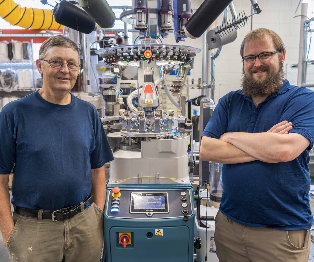 Two men stand next to a sock machine in Ashland, New Hampshire