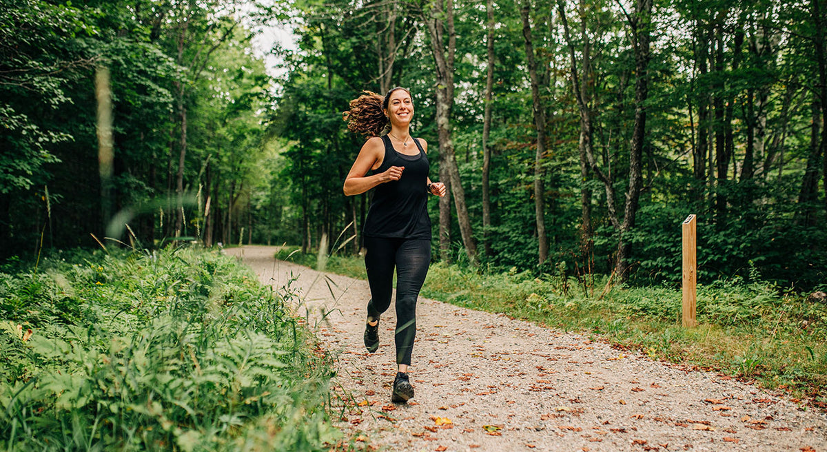 woman running wearing merino wool black racer back tank