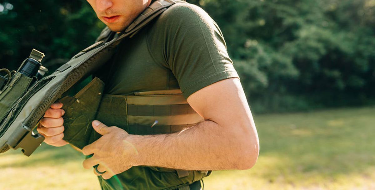 man putting on  bullet proof vest wearing a micro weight olive drab raglan tshirt