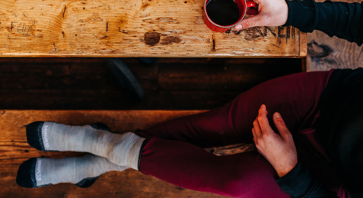 man sitting drinking coffee wearing midweight burgundy base layer bottoms