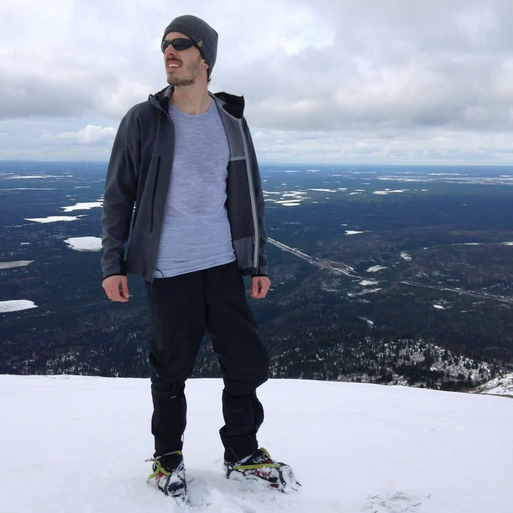 A man stands on a snowy summit in snowshoes. He wears the microweight Merino wool t shirt, the perfect first layer in any season! Raglan sleeves and side panels create a garment that moves with you 