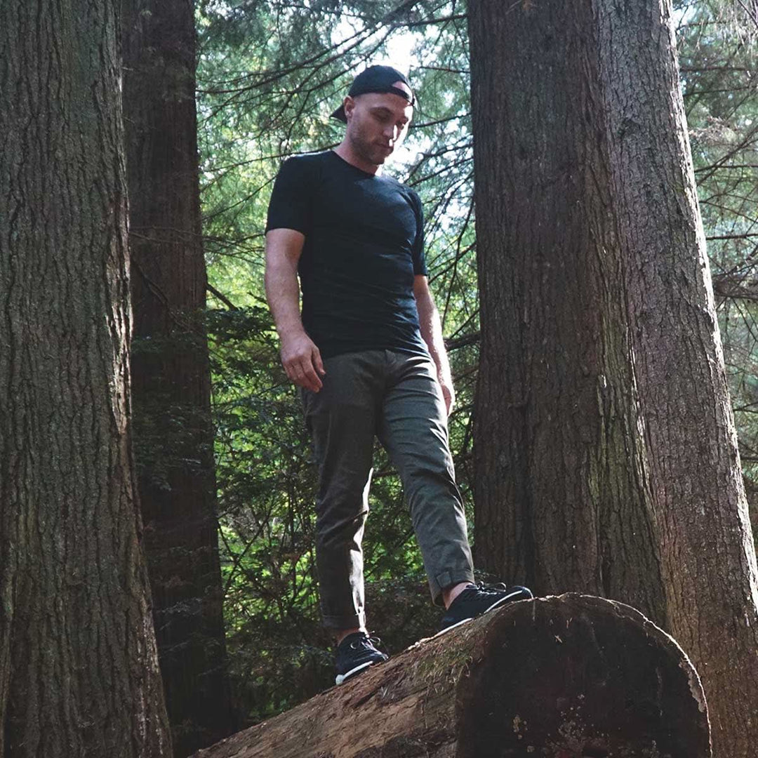 A man stands on a log and models the microweight Merino wool t shirt, your perfect choice for hitting the gym or setting foot on the trails. Raglan sleeves and side panels create a garment that moves with you 