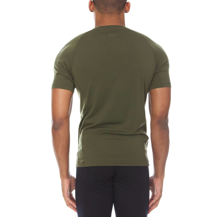 A man models the microweight merino wool t shirt, your perfect choice for hitting the gym or setting foot on the trails. Raglan sleeves and side panels create a garment that moves with you, back view 