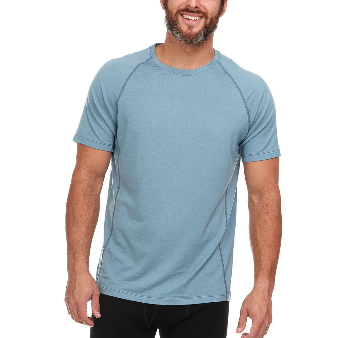 Front view with camera angle of a man modeling the microweight Merino wool t shirt in slate blue, your perfect choice for hitting the gym or setting foot on the trails. Raglan sleeves and side panels create a garment that moves with you 