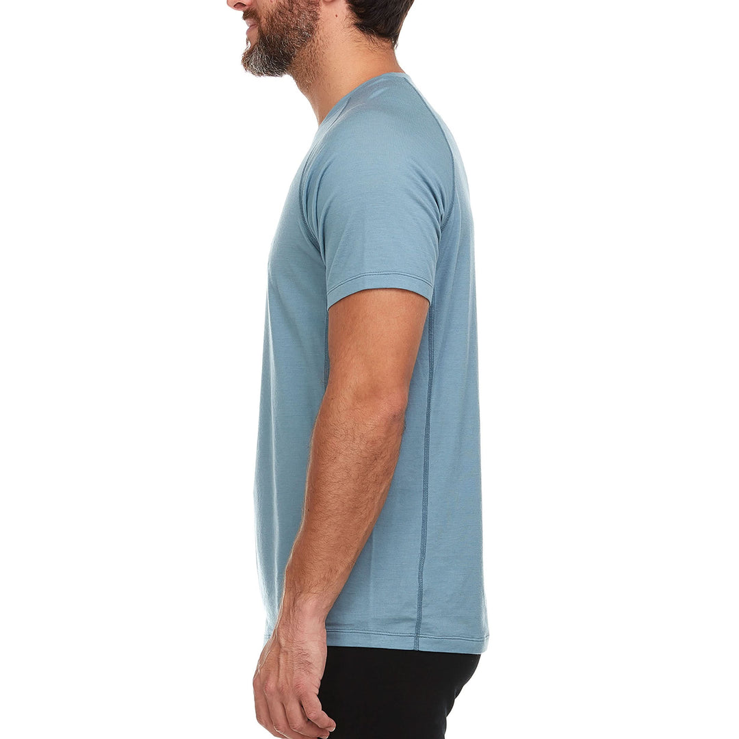 Side view of a man modeling the microweight Merino wool t shirt in slate blue, your perfect choice for hitting the gym or setting foot on the trails. Raglan sleeves and side panels create a garment that moves with you 