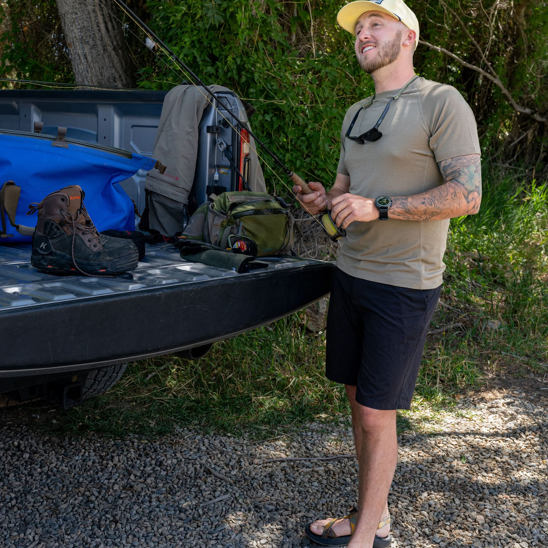 A man readies his fishing rod and models the microweight Merino wool t shirt, your perfect choice for hitting the gym or setting foot on the trails. Raglan sleeves and side panels create a garment that moves with you 