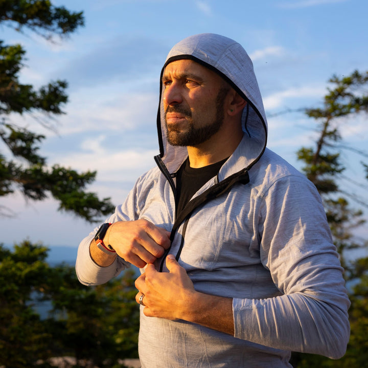 A man zips up the super light microweight merino wool quarter zip sun hoodie.  
