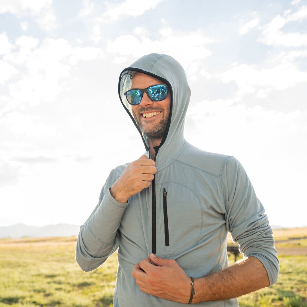 A man zips up the super light microweight merino wool quarter zip sun hoodie. 