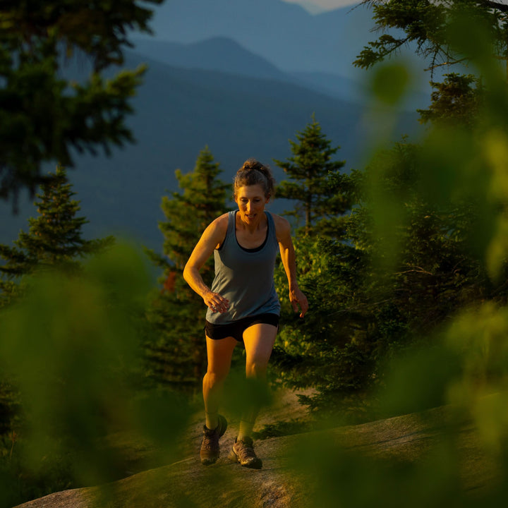 Womens microweight tank top super light merino wool for summer, woman hiking on a mountain trail 
