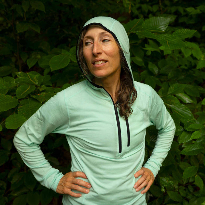 Woman runner wears a microweight 1/4 zip merino sun hoodie 