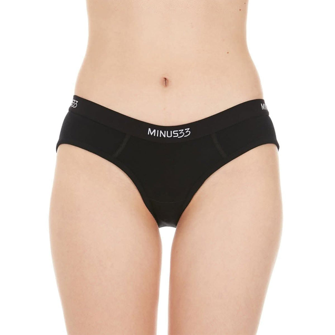 A woman models a pair of super soft merino wool bikini brief underwear. Light and breathable, these briefs feature a 1-inch woven sport elastic band, and high cut leg openings for a better range of movement. Front view. #color_black