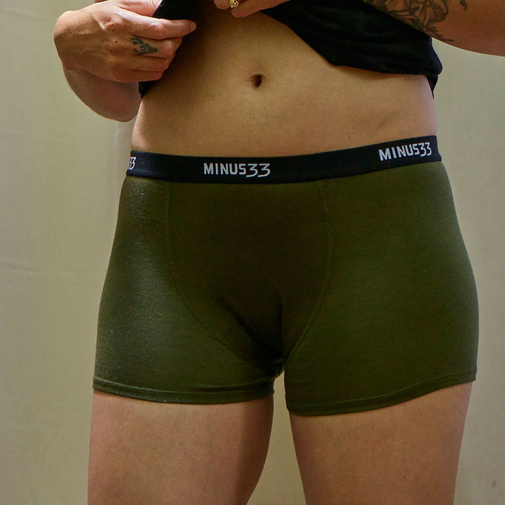 A woman models the microweight merino wool boyshorts. The boyshorts have a one inch inseam and a one inch woven sport elastic waistband. Lifestyle view. 