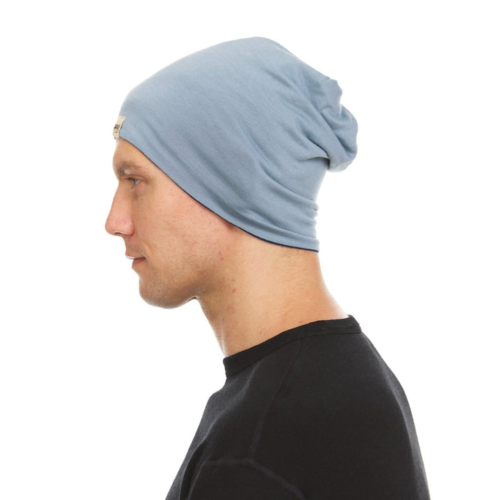 Side profile view of a male model wearing a navy and slate blue reversible merino wool blend beanie 