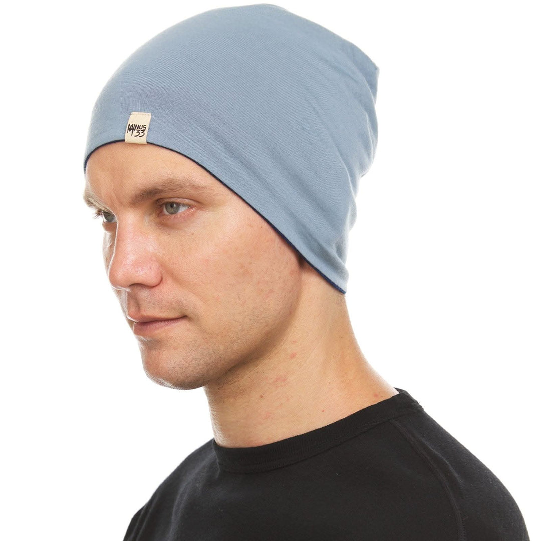 Alternate side view of a male model wearing a navy and slate blue reversible merino wool blend beanie 