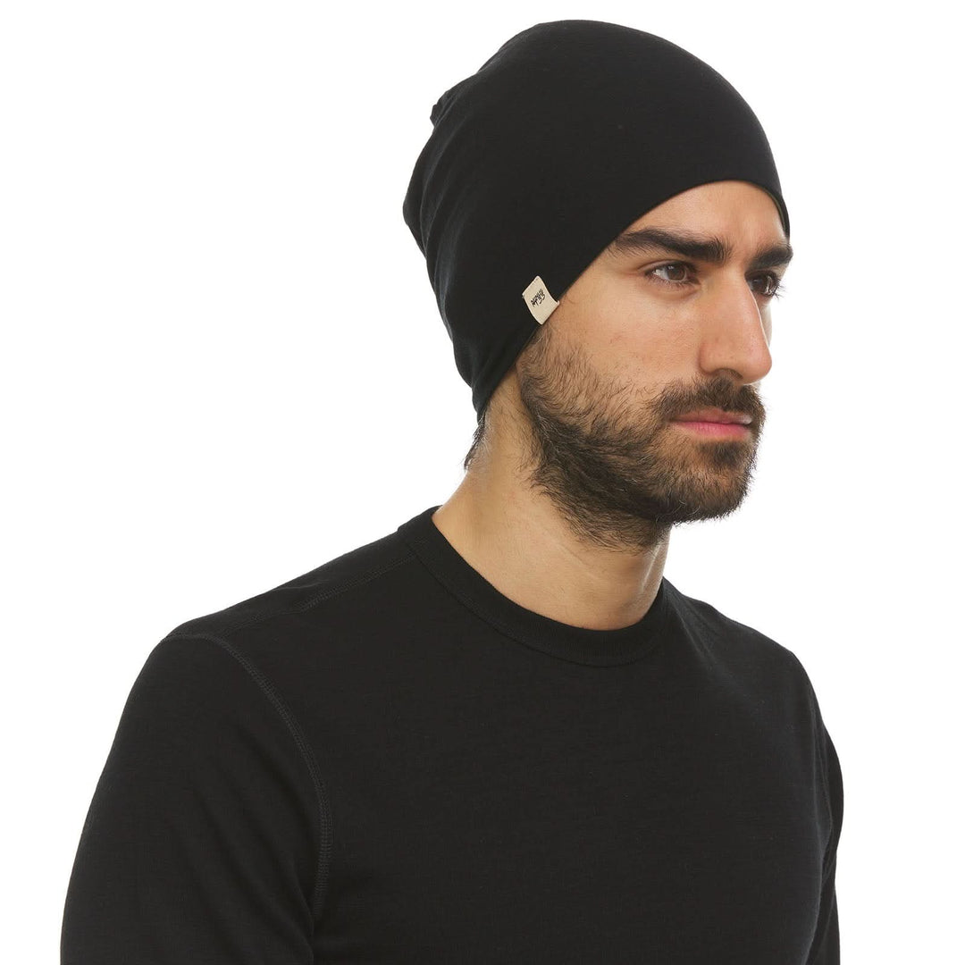 Side profile view of a male model wearing an olive drab green and black reversible merino wool blend beanie 