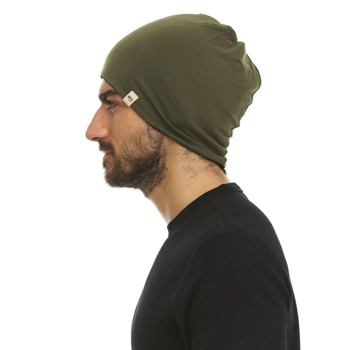 Alternate side view of a male model wearing an olive drab green and black reversible merino wool blend beanie 