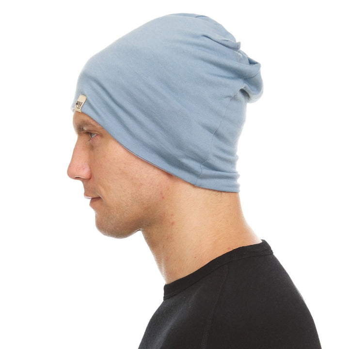 Opposite side view of a male model wearing a slate blue and ash gray reversible merino wool blend beanie 