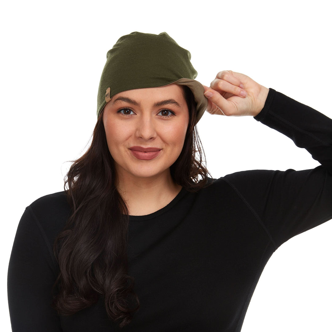 Side view of a male model wearing a tan and olive drab reversible merino wool blend beanie with the cuff flipped up 