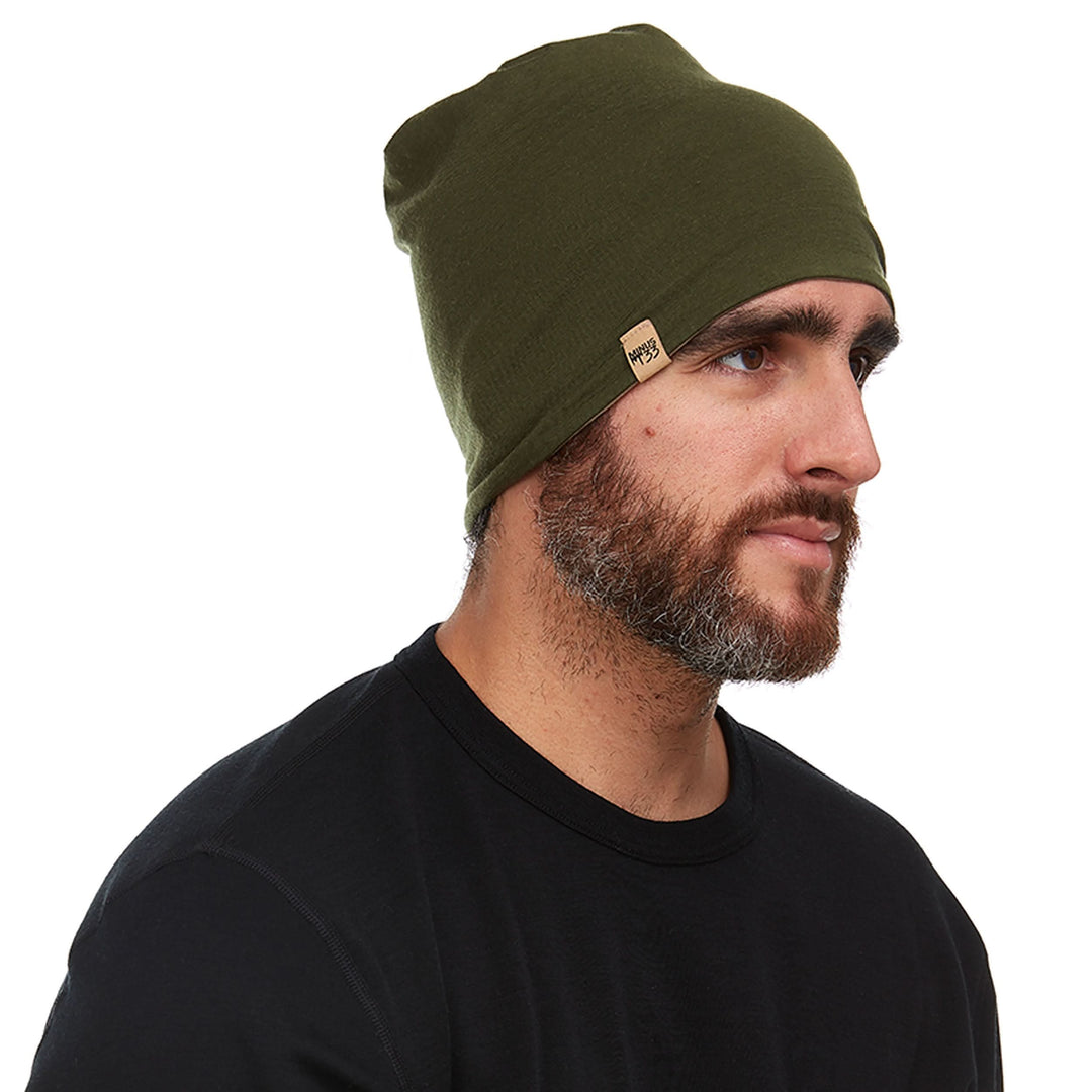 Side profile view of a male model wearing the olive drab side of a tan reversible merino wool blend beanie 
