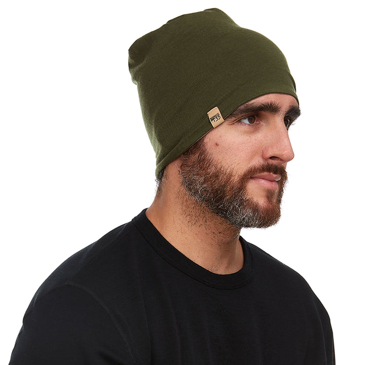 Side profile view of a male model wearing the olive drab side of a tan reversible merino wool blend beanie 