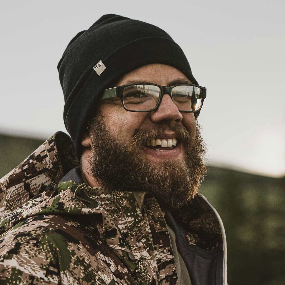 A man models the lightweight, double-layered, hundred percent, super soft merino wool beanie perfect for fall, winter, and spring. This hat is perfect for a hike up the mountain or a walk around the block, front view while hunting 