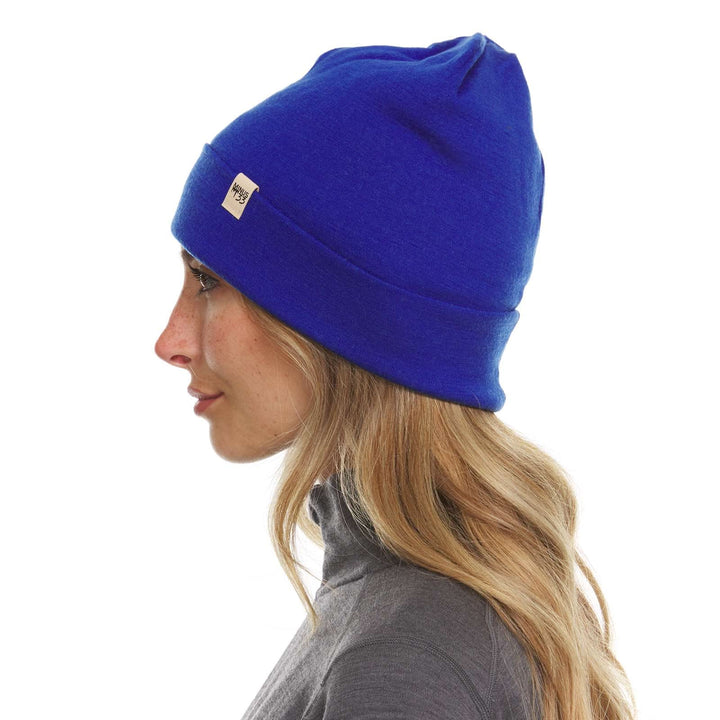 A woman models the lightweight, double-layered, hundred percent, super soft merino wool beanie perfect for fall, winter, and spring. This hat is perfect for a hike up the mountain or a walk around the block, right-facing side view 