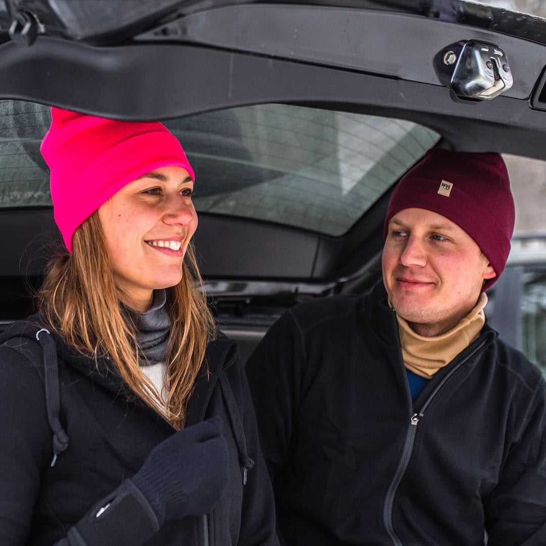 Two people sit in an open car trunk adjusting their gear. They&