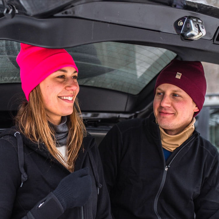 Two people sit in an open car trunk adjusting their gear. They&