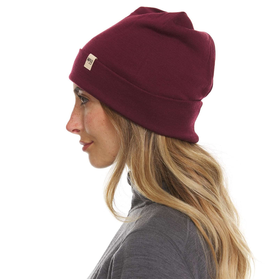 A woman models a lightweight, double-layered, hundred percent, super soft merino wool beanie perfect for fall, winter, and spring. This hat is perfect for a hike up the mountain or a walk around the block, right-facing side view 