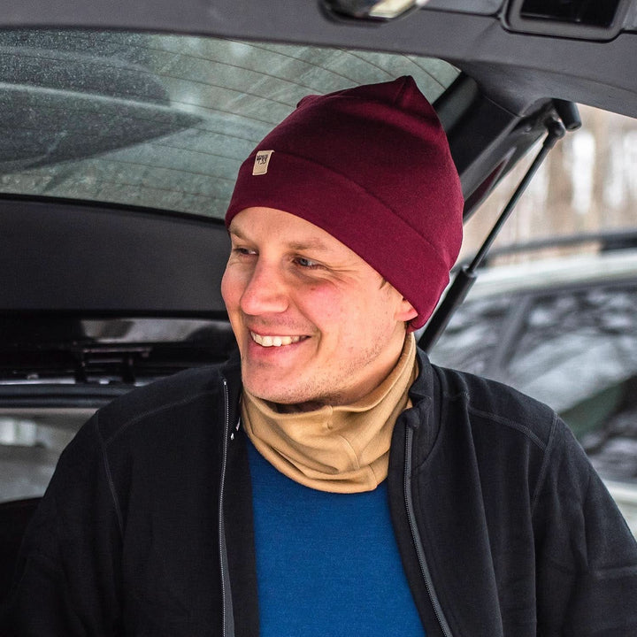 A man models a lightweight, double-layered, hundred percent, super soft merino wool beanie with a midweight wool neck gaiter, midweight base layer, and heavyweight zip-up sweater. This hat is perfect for a hike up the mountain or a walk around the block!
