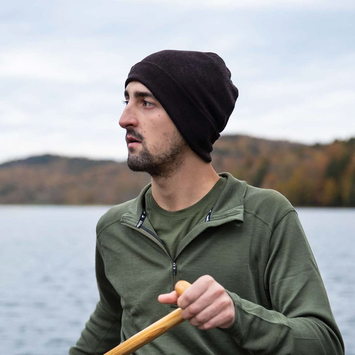 A man models the lightweight, double-layered, hundred percent, super soft merino wool beanie while canoeing the open waters. This hat is perfect for a hike up the mountain or a walk around the block!
