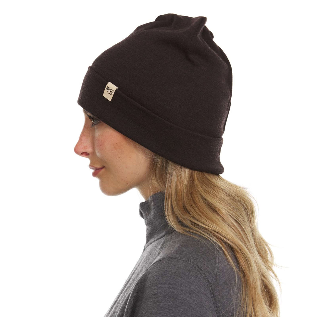 A woman models the lightweight, double-layered, hundred percent, super soft merino wool beanie perfect for fall, winter, and spring. This hat is perfect for a hike up the mountain or a walk around the block, right-facing side view 