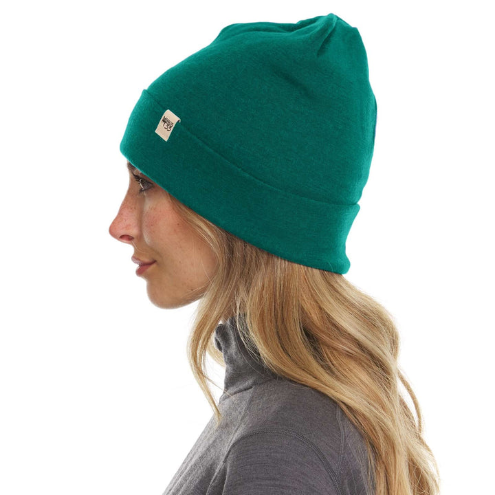 A woman models a lightweight, double-layered, hundred percent, super soft merino wool beanie perfect for fall, winter, and spring. This hat is perfect for a hike up the mountain or a walk around the block, right-facing side view 