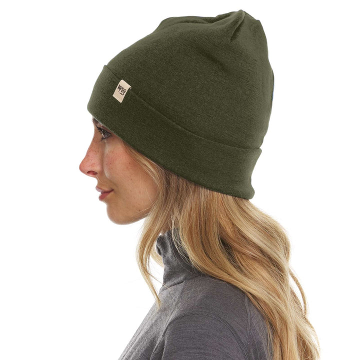 A woman models the lightweight, double-layered, hundred percent, super soft merino wool beanie perfect for fall, winter, and spring. This hat is perfect for a hike up the mountain or a walk around the block, right-facing side view 