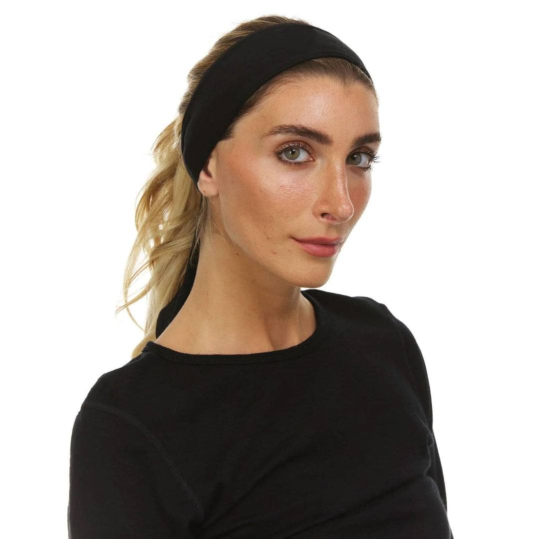 Close-up front three-quarter view of a woman wearing a wide black merino wool tie headband over a blonde ponytail, paired with a black long-sleeve crew-neck top