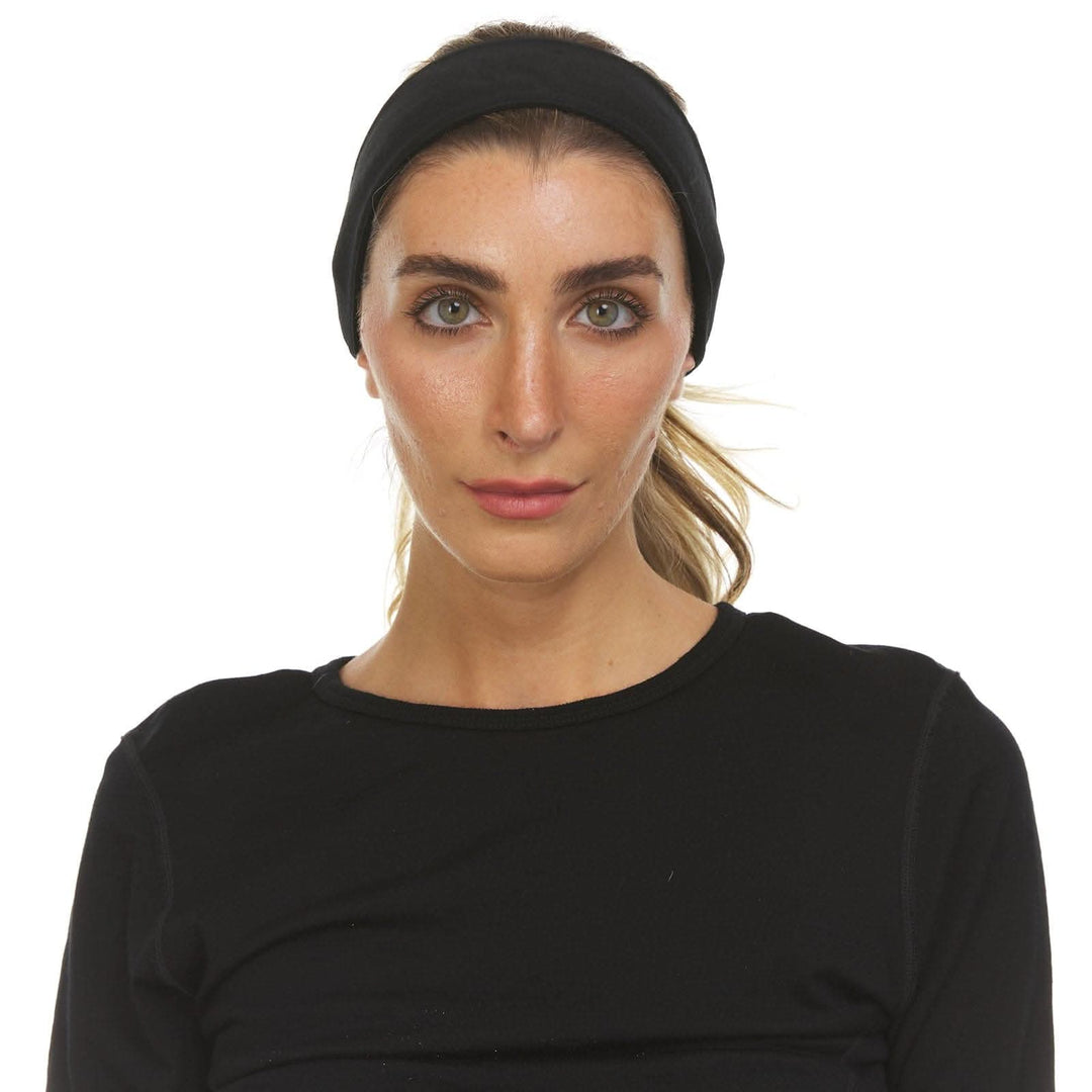 Close-up straight-on front view of a woman wearing a wide black merino wool tie headband across her hairline, with her blonde ponytail visible above a black crew-neck top