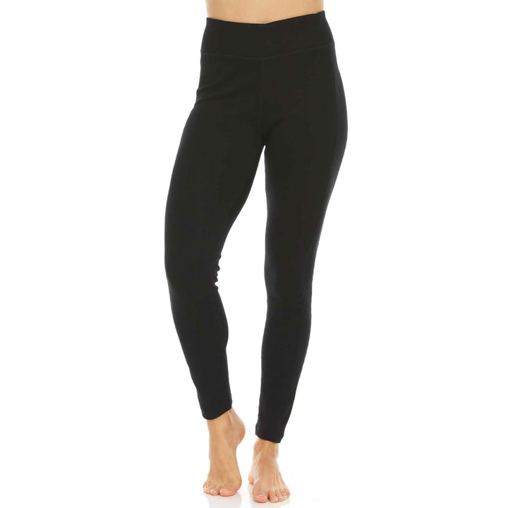 Front view from waist to feet of a woman wearing black Woolverino micro weight merino wool leggings, showing the wide waistband, fitted full-length legs, ankle hems, and one heel raised
