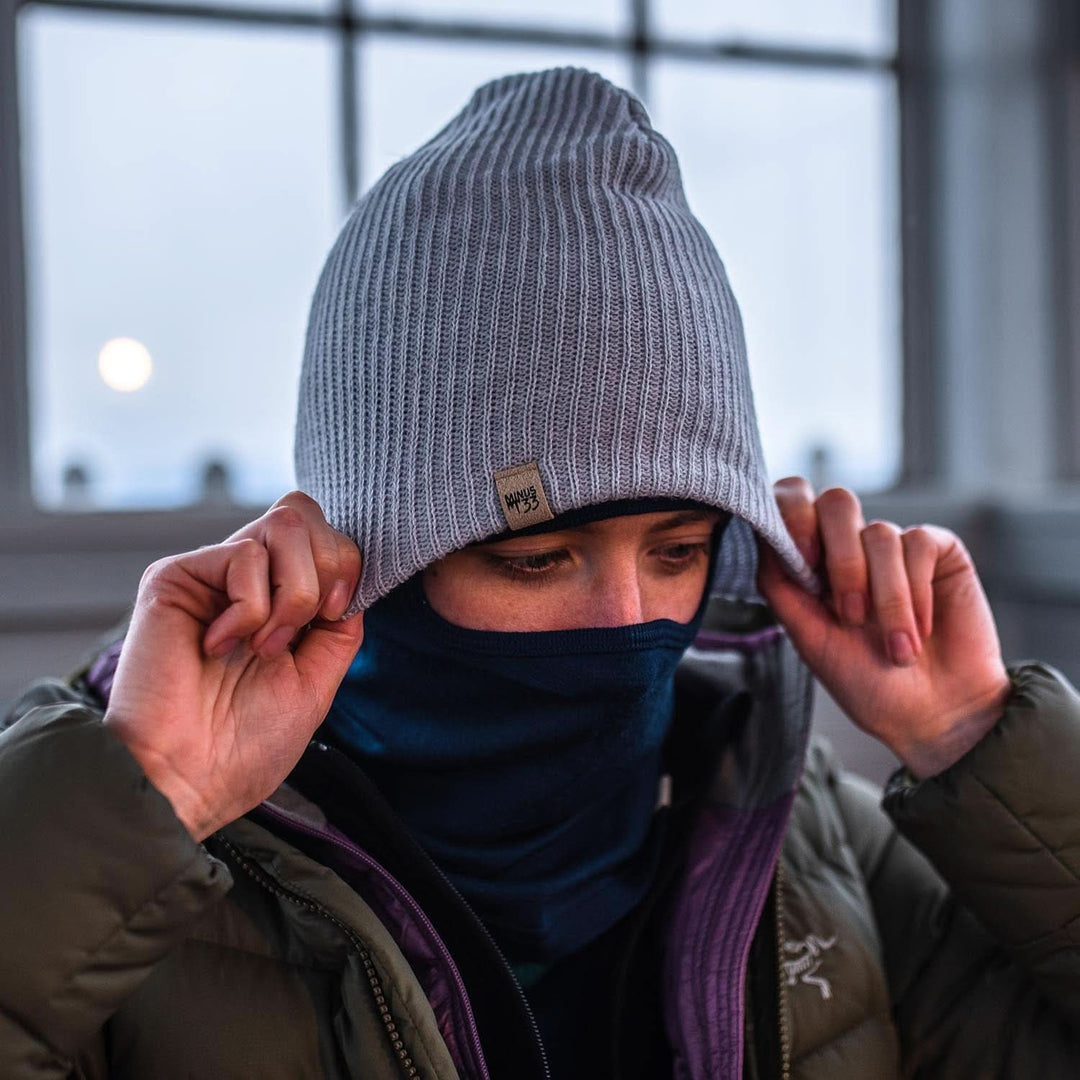 A person pulls on the midweight hundred percent merino wool beanie over their midweight balaclava 
