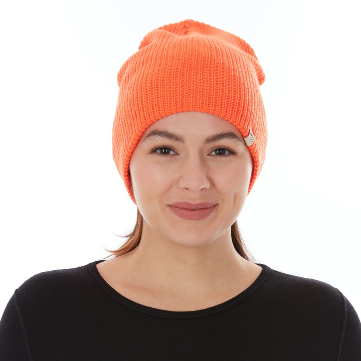 Front three-quarter view of a female model wearing a blaze orange midweight 100% merino wool beanie with a folded cuff 