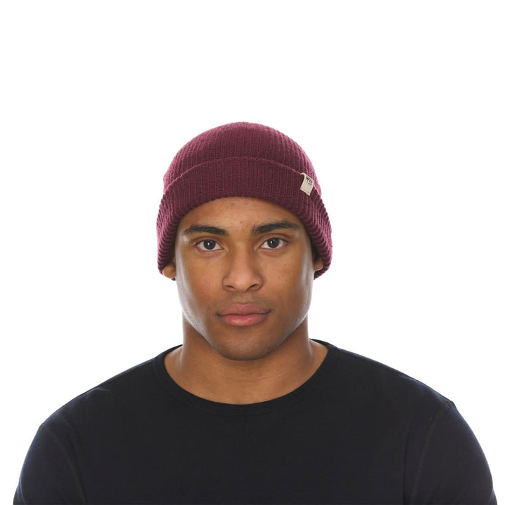 A man models the midweight hundred percent merino wool beanie 
