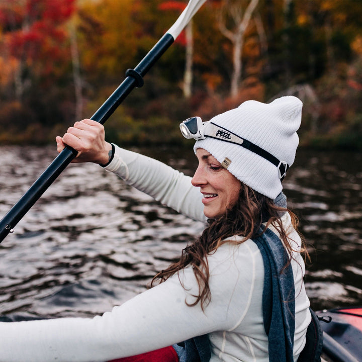 A woman kayaks in her midweight hundred percent merino wool beanie 