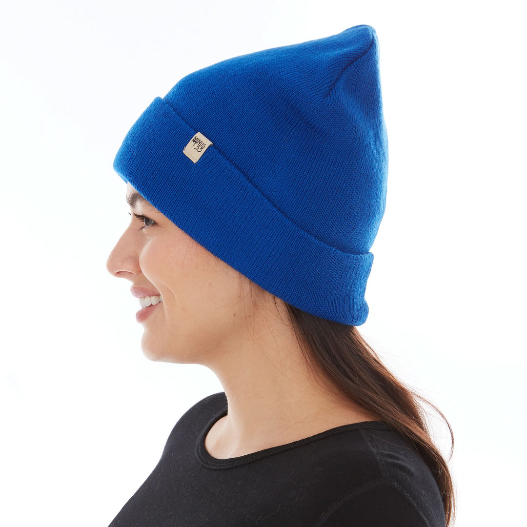 Side profile view of a female model wearing a royal blue midweight double-layer 100% merino wool beanie 