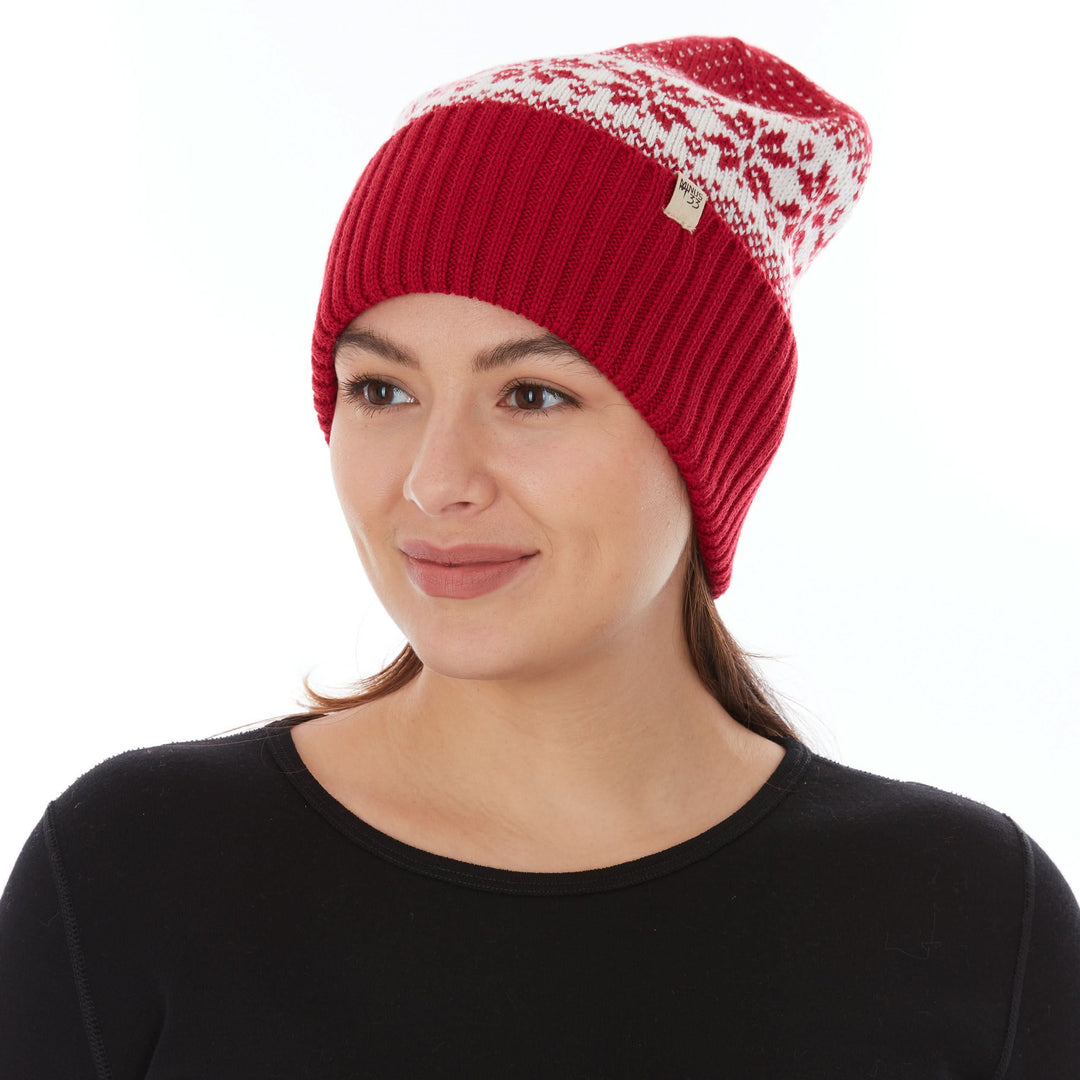 Front three-quarter view of a female model wearing a true red and natural cream snowflake-patterned midweight double-layer merino wool beanie 