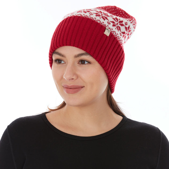 Front three-quarter view of a female model wearing a true red and natural cream snowflake-patterned midweight double-layer merino wool beanie 