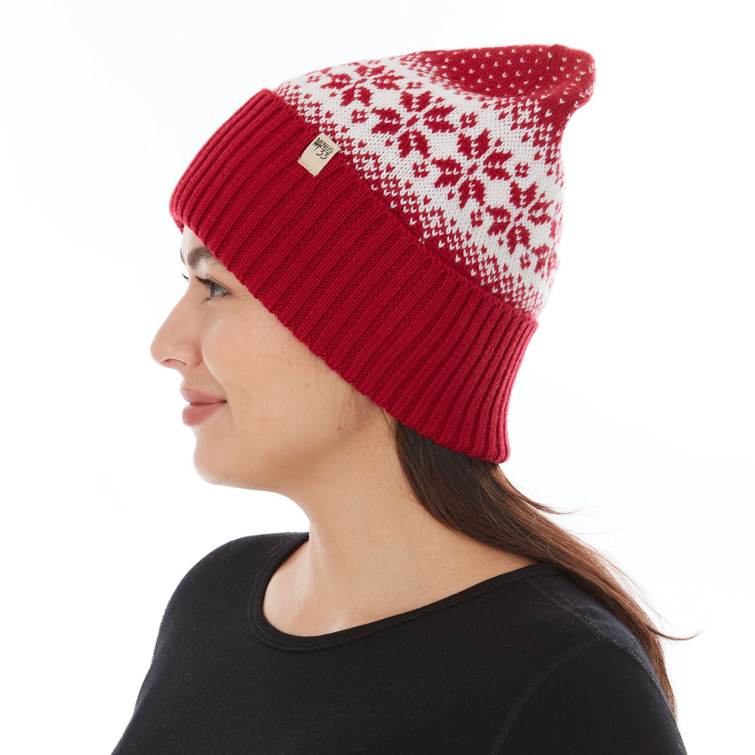 Side profile view of a female model wearing a true red and natural cream snowflake-patterned midweight double-layer merino wool beanie 