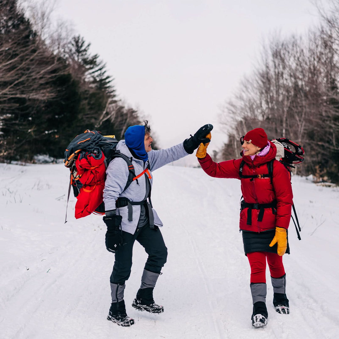 A man and a woman walk down the snowy mountain. The man is modeling the heavyweight brushed wool Kodiak Fleece Hoodie, crafted with thumbholes and a drawstring to bundle you up for wicked cold days! 