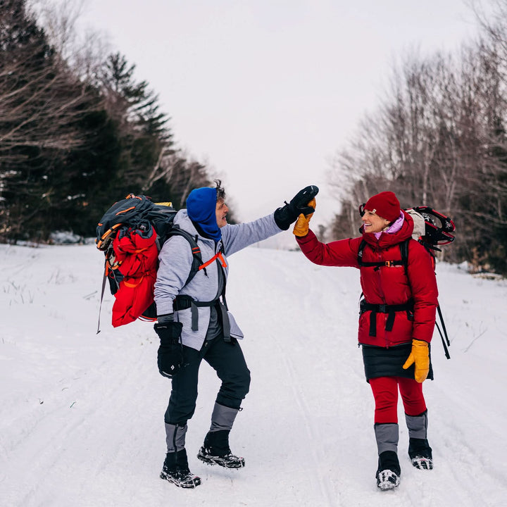 A man and a woman walk down the snowy mountain. The man is modeling the heavyweight brushed wool Kodiak Fleece Hoodie, crafted with thumbholes and a drawstring to bundle you up for wicked cold days! 
