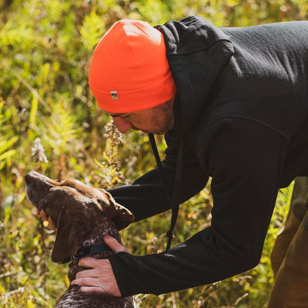 A man pets his hunting dog while wearing the heavyweight brushed wool Kodiak Fleece Hoodie, crafted with thumbholes and a drawstring to bundle you up for wicked cold days! 