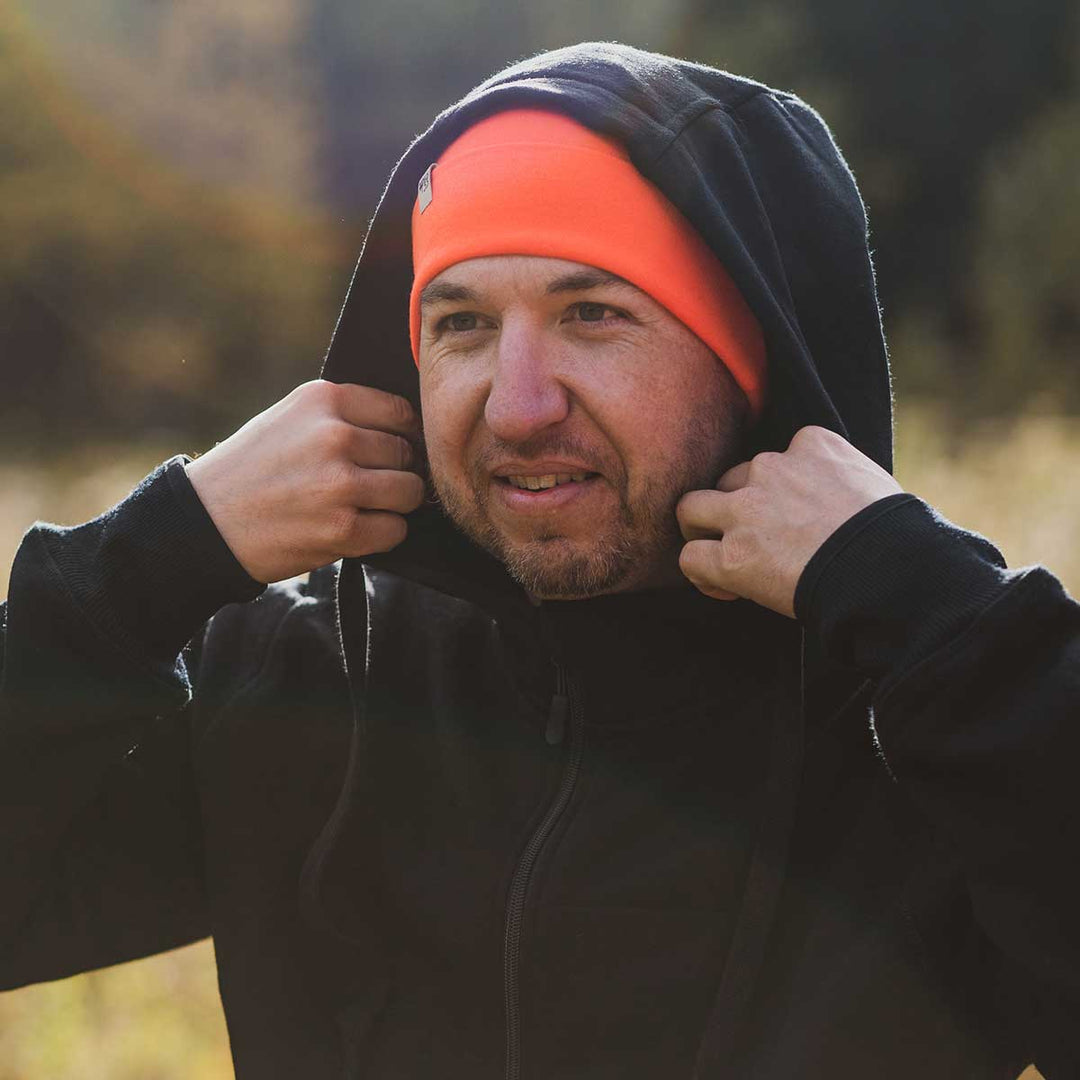 A man adjusts his hood on the heavyweight brushed wool Kodiak Fleece Hoodie, crafted with thumbholes and a drawstring to bundle you up for wicked cold days! 
